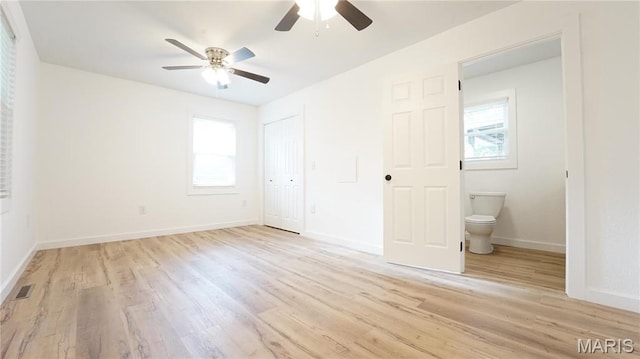unfurnished bedroom featuring light wood-type flooring, multiple windows, a closet, and baseboards