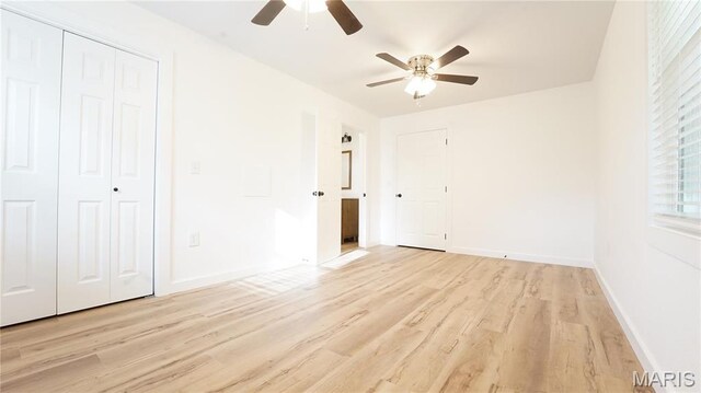 unfurnished bedroom featuring light wood finished floors, baseboards, a ceiling fan, and a closet