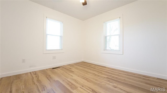 spare room with light wood-type flooring, baseboards, and a ceiling fan