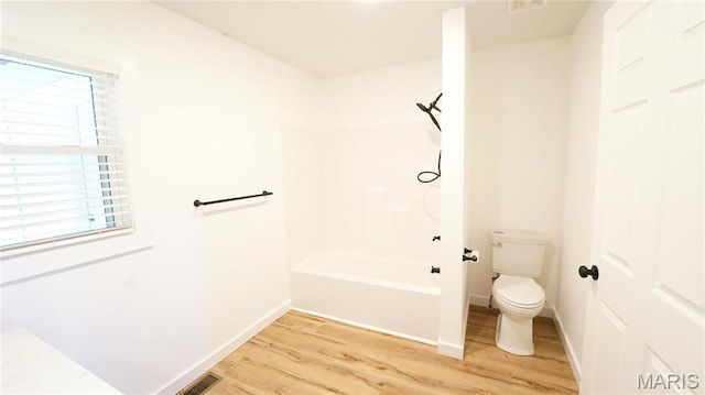 bathroom featuring wood finished floors, toilet, baseboards, and shower / bathtub combination