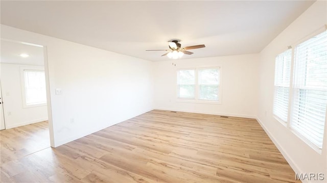 spare room with light wood-style floors, a ceiling fan, and baseboards