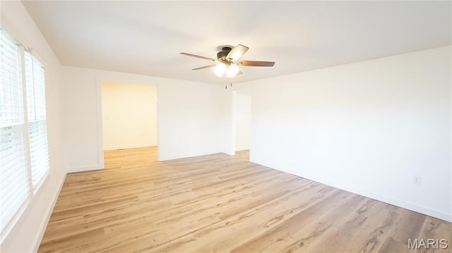 unfurnished room featuring light wood-type flooring, a ceiling fan, and baseboards