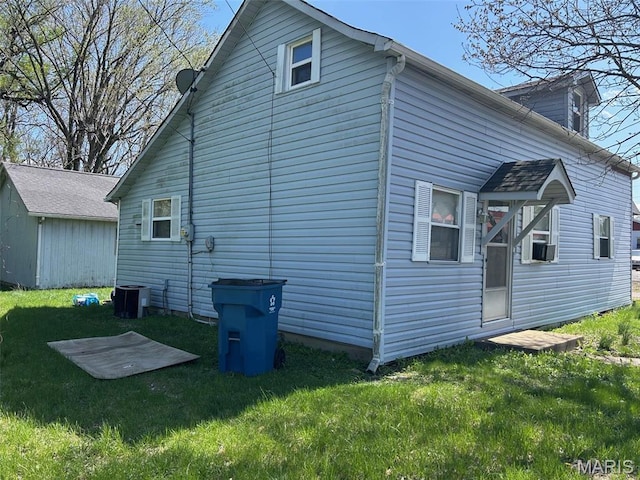 back of house with a lawn, central air condition unit, and an outbuilding