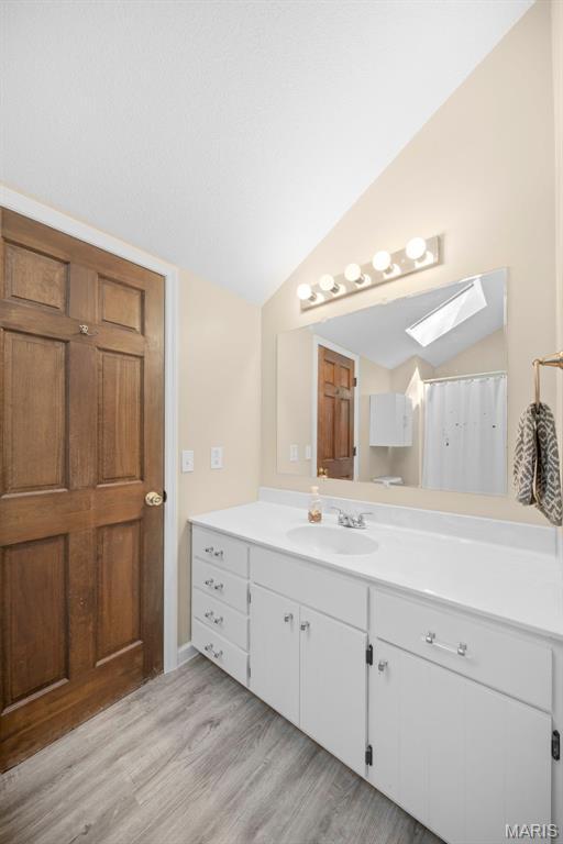 5 Cedar Fork Ct, Defiance, MO 63341 - full bathroom featuring a skylight, lofted ceiling, vanity, and wood finished floors