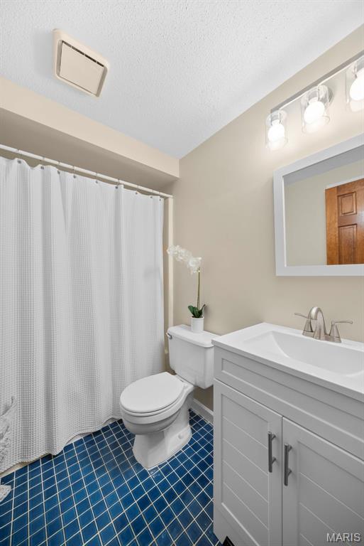 5 Cedar Fork Ct, Defiance, MO 63341 - full bath with tile patterned flooring, toilet, vanity, and a textured ceiling