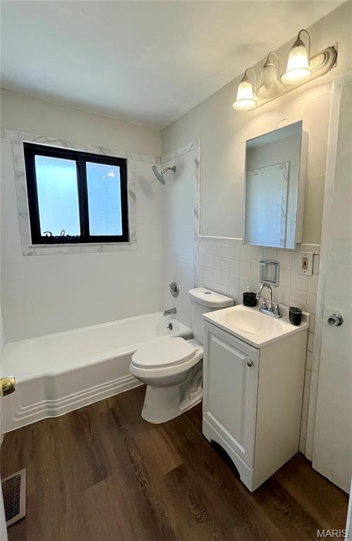 11606 Herefordshire Dr, Saint Louis, MO 63138 - bathroom featuring wood finished floors, bathtub / shower combination, tile walls, toilet, and vanity