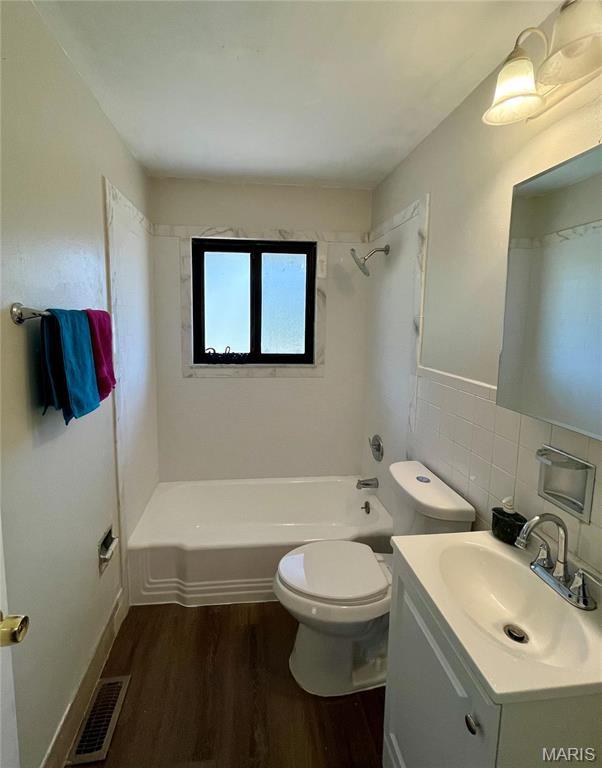 11606 Herefordshire Dr, Saint Louis, MO 63138 - full bathroom with wood finished floors, toilet, shower / tub combination, vanity, and tile walls