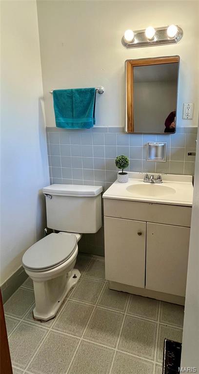 11606 Herefordshire Dr, Saint Louis, MO 63138 - half bathroom featuring toilet, vanity, and tile walls