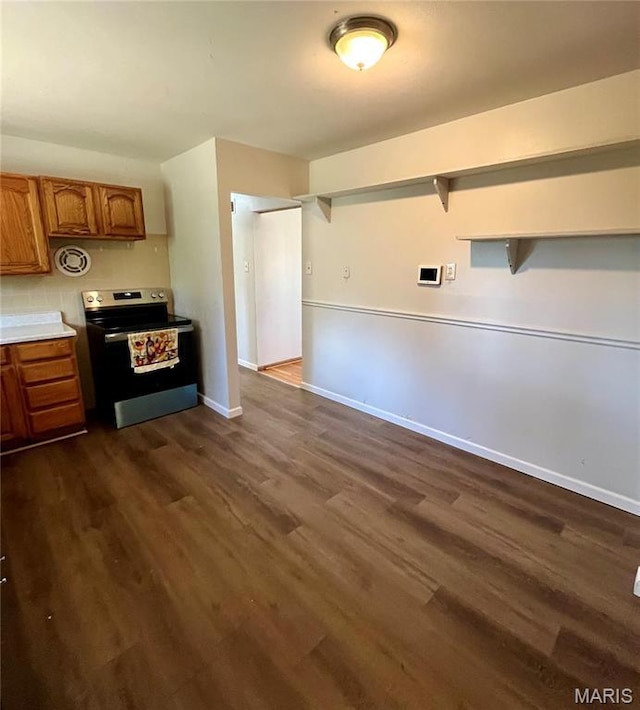 11606 Herefordshire Dr, Saint Louis, MO 63138 - kitchen with stainless steel range with electric stovetop, brown cabinets, dark wood-style flooring, light countertops, and baseboards