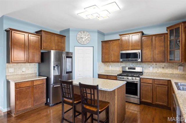 77 Brighton Park Dr, Saint Charles, MO 63303 - kitchen featuring appliances with stainless steel finishes, tasteful backsplash, dark wood-style floors, glass insert cabinets, and a kitchen island