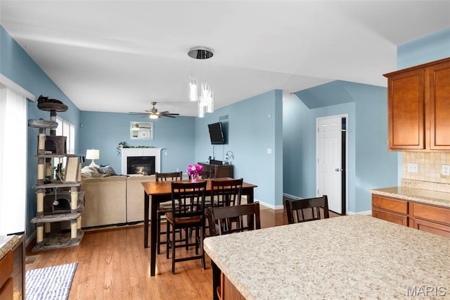 77 Brighton Park Dr, Saint Charles, MO 63303 - kitchen with ceiling fan, a glass covered fireplace, light countertops, decorative backsplash, and light wood-style flooring