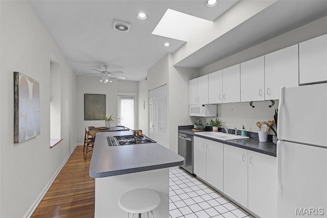 5858 Nina Pl Unit 3E, Saint Louis, MO 63112 - kitchen featuring appliances with stainless steel finishes, a sink, a kitchen island, a ceiling fan, and white cabinetry