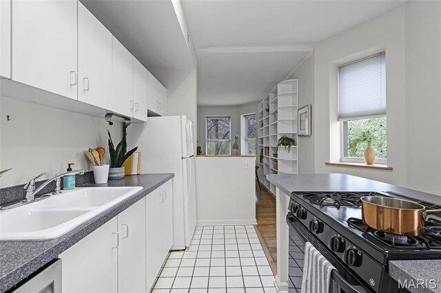 5858 Nina Pl Unit 3E, Saint Louis, MO 63112 - kitchen featuring black range with gas stovetop, a sink, plenty of natural light, and white cabinetry