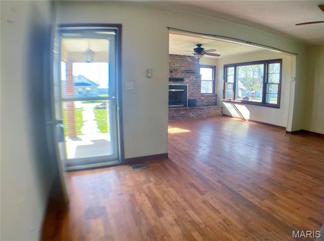 708 Locust St, Edgar Springs, MO 65462 - unfurnished living room featuring a ceiling fan, wood finished floors, baseboards, a brick fireplace, and brick wall