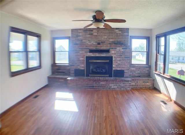 708 Locust St, Edgar Springs, MO 65462 - unfurnished living room featuring wood finished floors, a ceiling fan, a brick fireplace, baseboards, and a textured ceiling