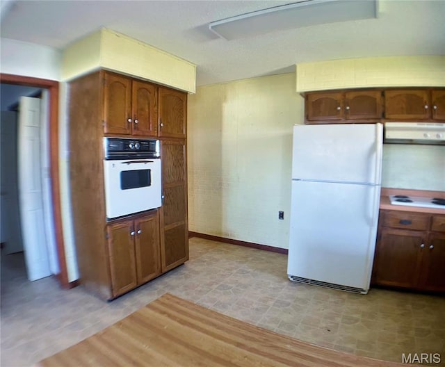 708 Locust St, Edgar Springs, MO 65462 - kitchen with white appliances, under cabinet range hood, brown cabinets, and light wood finished floors