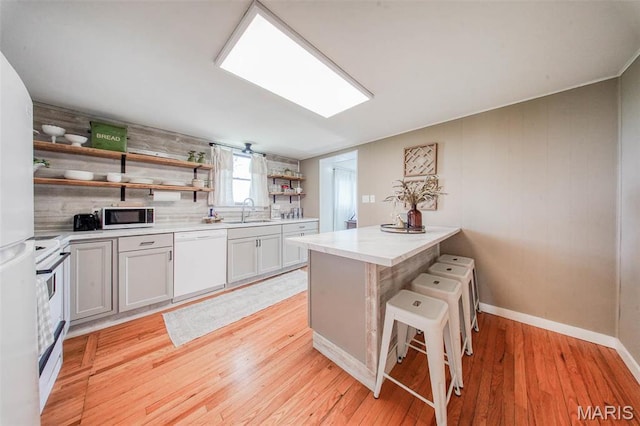 15227 County Road 1110, St James, MO 65559 - kitchen featuring white appliances, open shelves, a sink, light countertops, and light wood-style floors