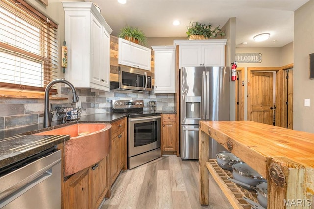 1318 Stormy Point Rd Unit 7, Branson, MO 65616 - kitchen featuring appliances with stainless steel finishes, a sink, white cabinets, decorative backsplash, and light wood-style flooring