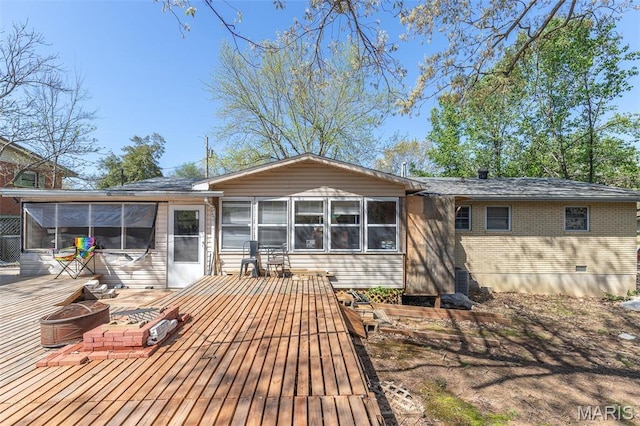 rear view of house featuring a sunroom, an outdoor fire pit, a wooden deck, and brick siding