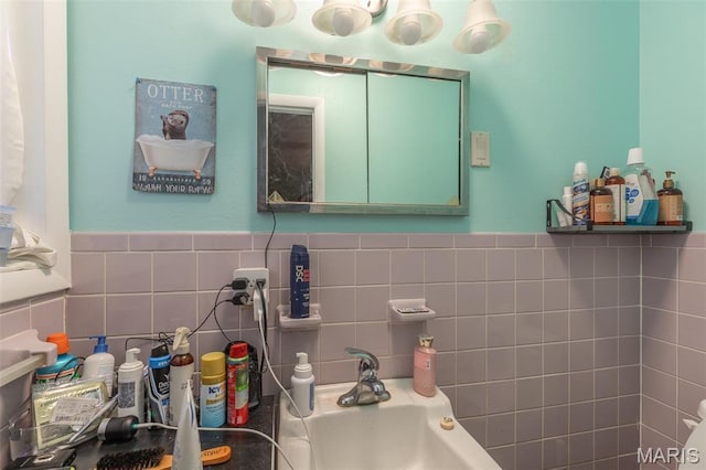 half bathroom with a sink, tile walls, and a wainscoted wall