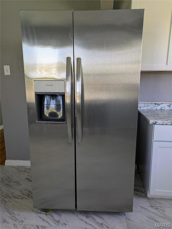 330 N Floridale Ave, Saint Louis, MO 63135 - kitchen view of stainless steel fridge with ice dispenser, white cabinets, light stone countertops, and baseboards