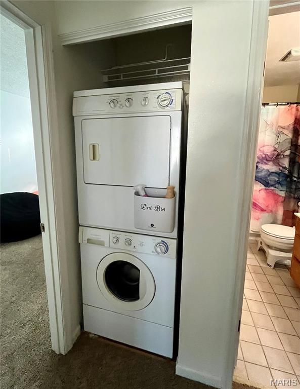1504 Swallow Dr, Saint Louis, MO 63144 - washroom featuring stacked washer and clothes dryer and tile patterned floors