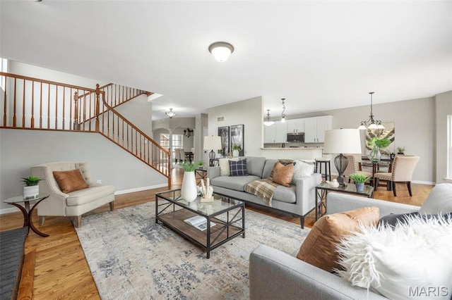 407 Forby Estates Dr, Eureka, MO 63025 - living area with stairway, a chandelier, light wood finished floors, and baseboards