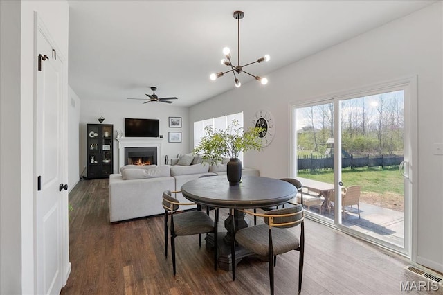 145 Pampano Ln, Saint Charles, MO 63301 - dining area featuring a ceiling fan, dark wood-style floors, a warm lit fireplace, and a chandelier