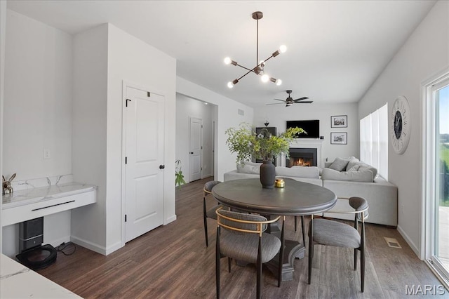 145 Pampano Ln, Saint Charles, MO 63301 - dining area featuring wood finished floors, a lit fireplace, a chandelier, ceiling fan, and baseboards
