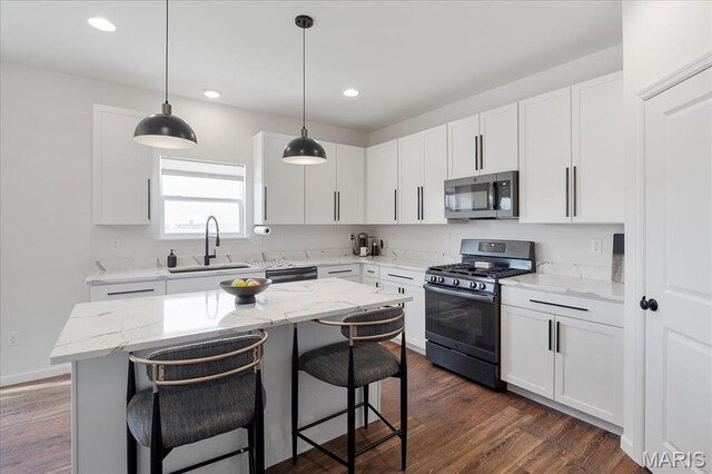145 Pampano Ln, Saint Charles, MO 63301 - kitchen with stainless steel appliances, a sink, a breakfast bar, light stone counters, and recessed lighting