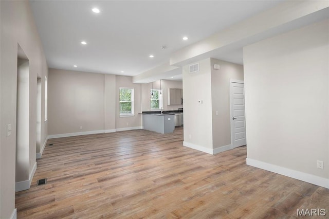 6800 Minnesota Ave, Saint Louis, MO 63111 - unfurnished living room with baseboards, light wood-type flooring, recessed lighting, and a sink