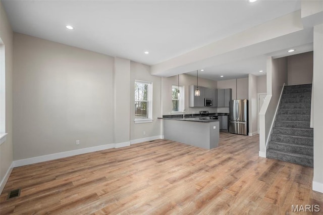 6800 Minnesota Ave, Saint Louis, MO 63111 - kitchen with appliances with stainless steel finishes, dark countertops, gray cabinetry, a peninsula, and light wood finished floors