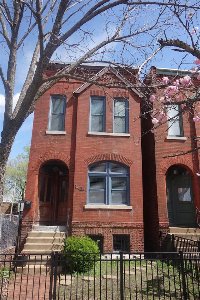 view of front facade with brick siding and a fenced front yard