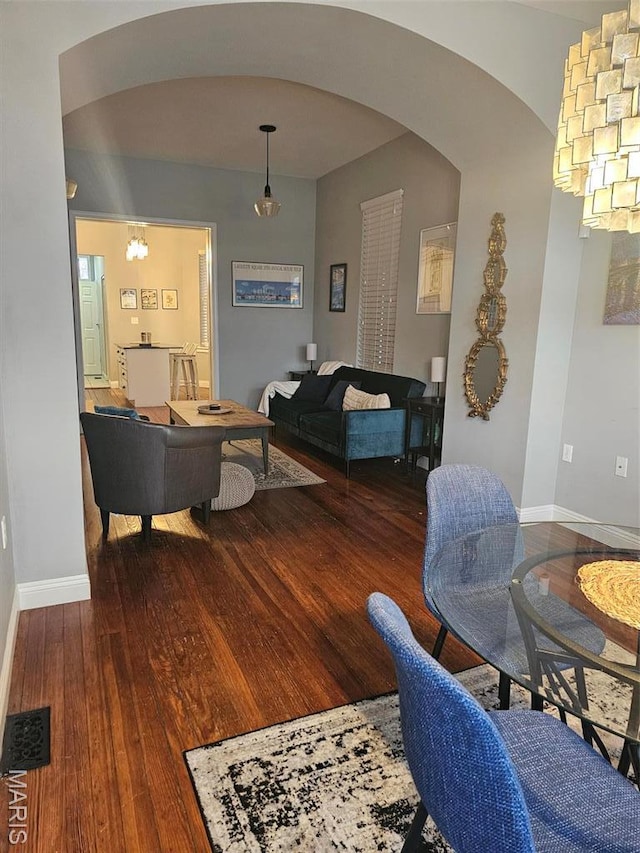 living room featuring arched walkways, hardwood / wood-style flooring, baseboards, and a chandelier