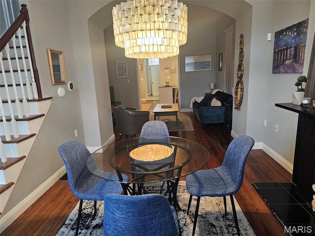dining area featuring arched walkways, wood finished floors, stairs, and baseboards