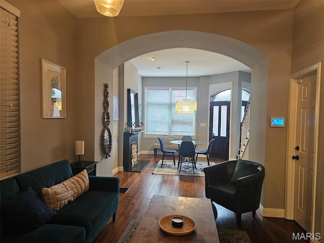 living area with arched walkways, dark wood finished floors, and baseboards