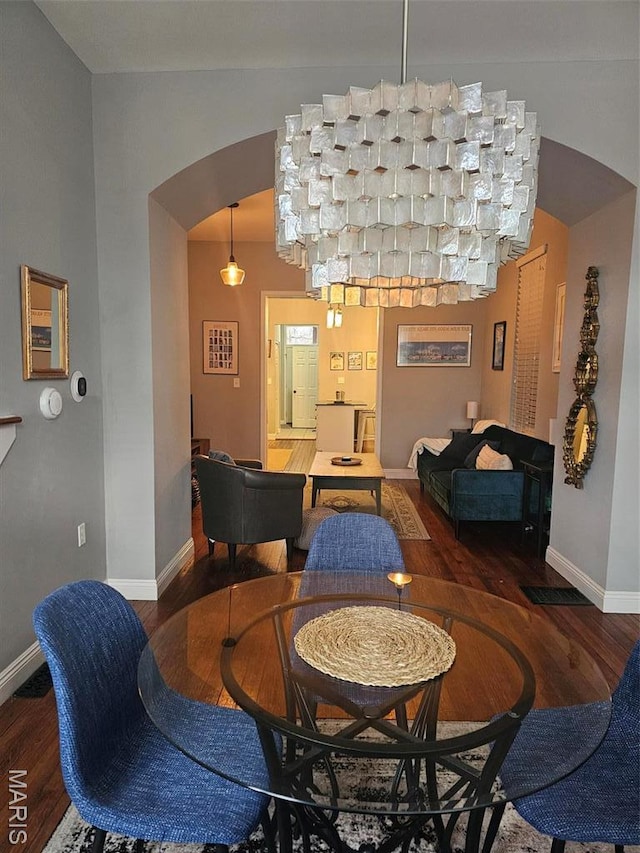 dining area featuring arched walkways, wood finished floors, and baseboards