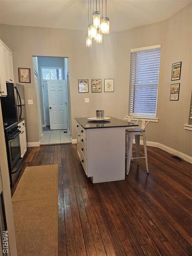 kitchen featuring stainless steel gas range, dark wood-type flooring, white cabinetry, dark countertops, and a chandelier