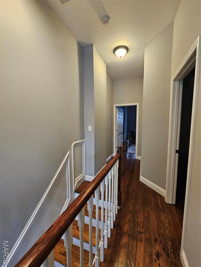 corridor with hardwood / wood-style floors, an upstairs landing, and baseboards