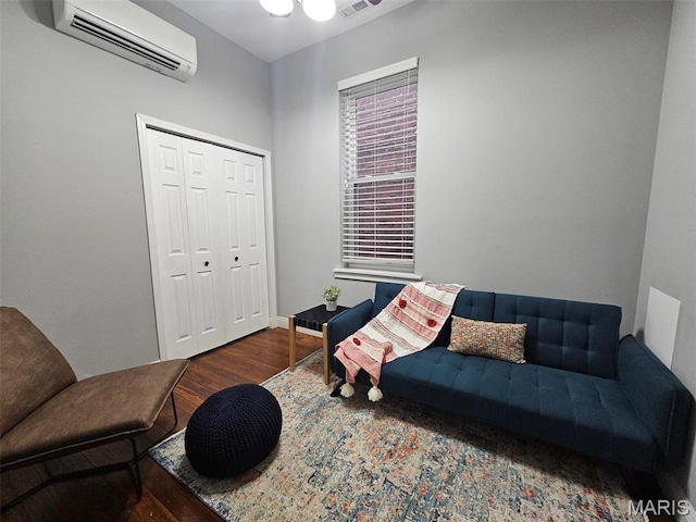 living room with an AC wall unit, wood finished floors, and baseboards