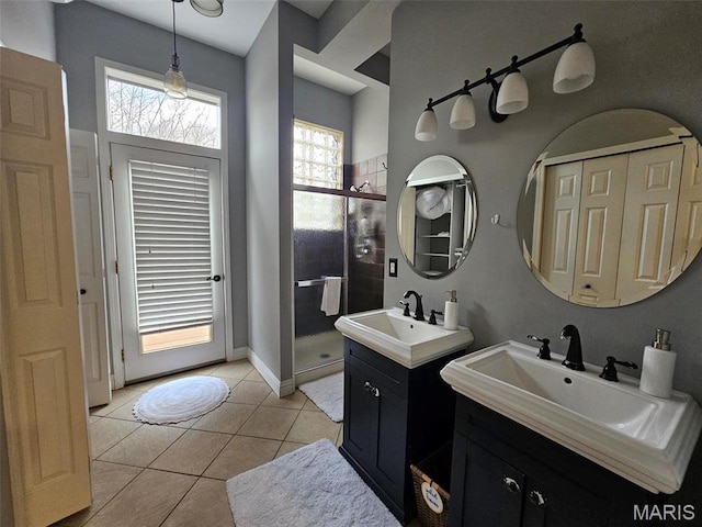 full bathroom featuring a stall shower, tile patterned floors, two vanities, and baseboards
