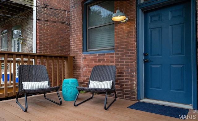view of exterior entry with brick siding and a wooden deck