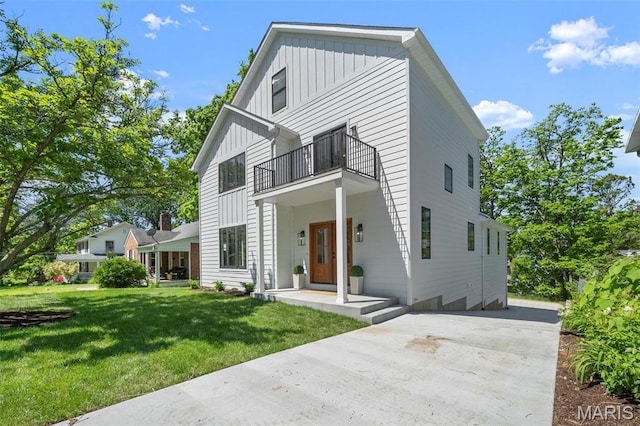 view of front of property with a balcony, board and batten siding, and a front lawn