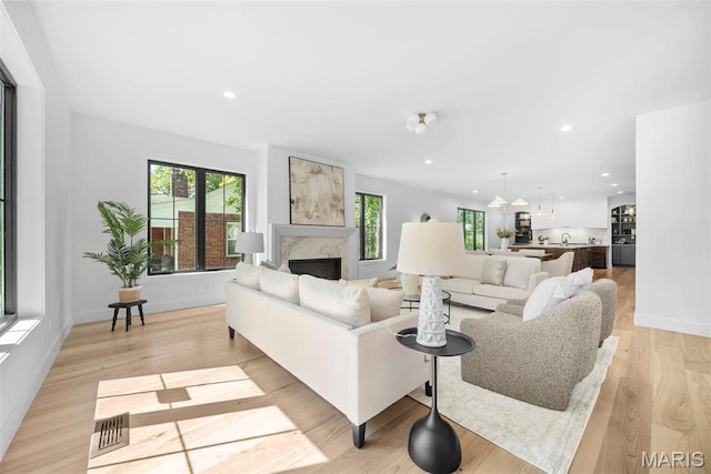 living room featuring a fireplace, recessed lighting, light wood-style flooring, and baseboards