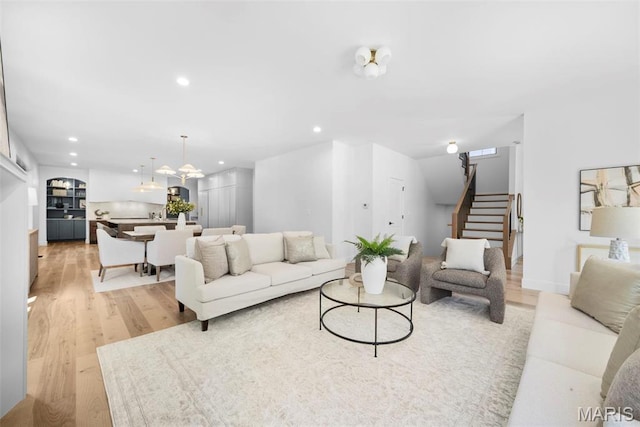 living room featuring stairs, light wood-type flooring, recessed lighting, and a chandelier