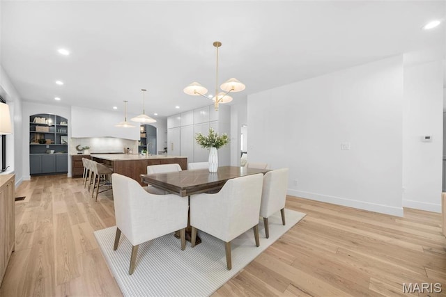 dining room with light wood-style flooring, recessed lighting, baseboards, and a chandelier