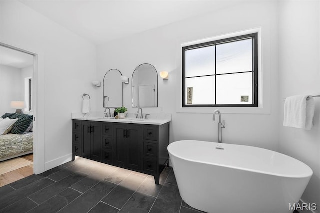 full bath featuring double vanity, a soaking tub, ensuite bathroom, and baseboards