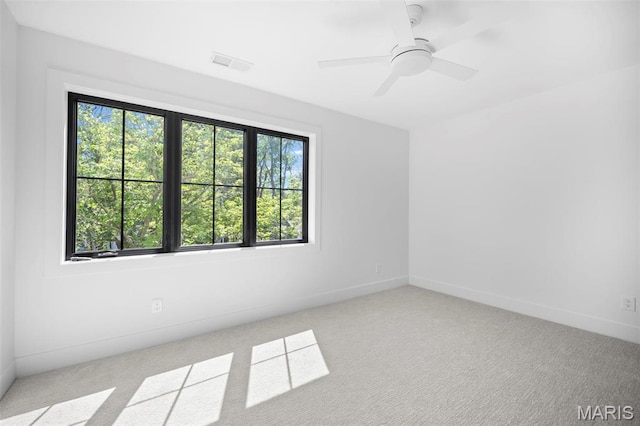 carpeted spare room featuring baseboards and a ceiling fan