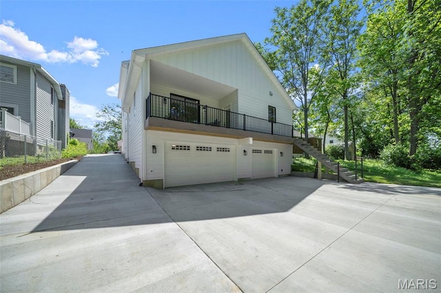 view of property exterior with an attached garage, concrete driveway, stairs, and board and batten siding