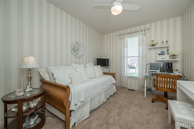 bedroom featuring a desk, light carpet, a ceiling fan, and wallpapered walls